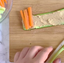 Adding the carrots and celery to a zucchini roll up