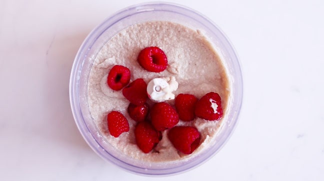 Food processor from the top with a dough and raspberries