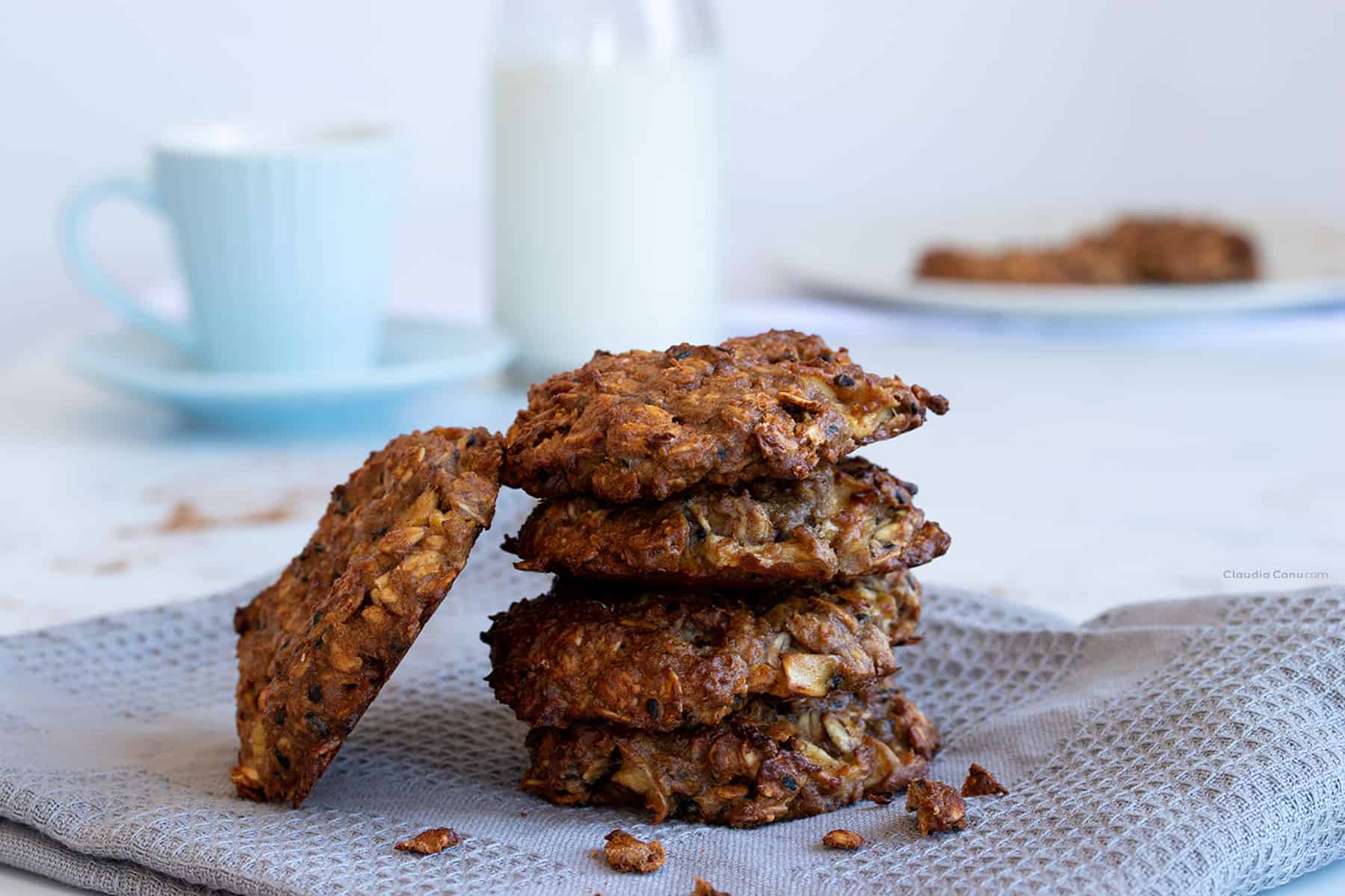 A pile of Oatmeal Cookies, a coffee mug and a bottle of milk