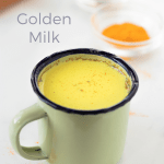 A green mug with golden milk inside