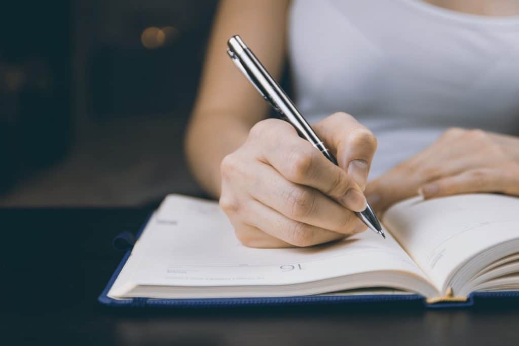 A woman's hand writing something on a notebook