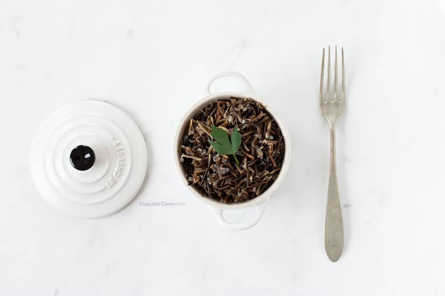 A white cocotte with black rice in it