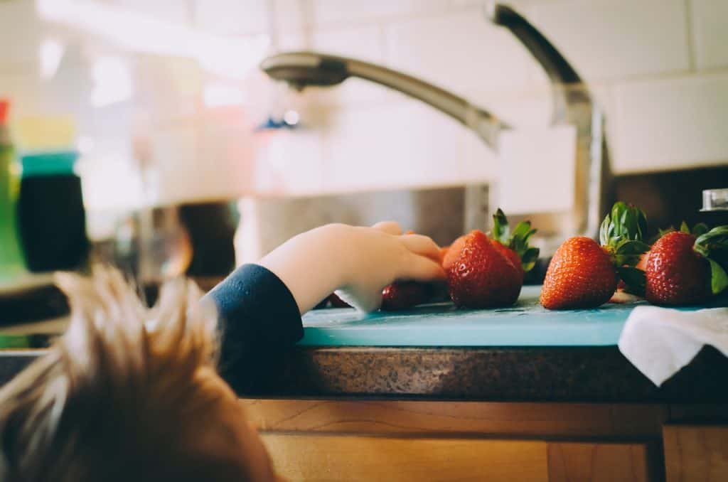 A child trying to reach for a strawberry