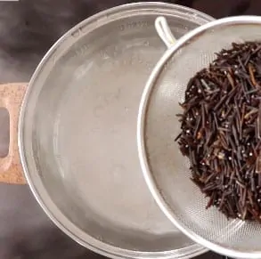 Pouring wild rice into a pot with boiling water