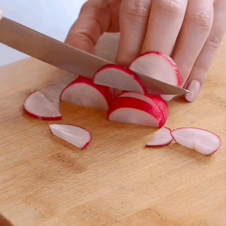 A hand cutting radishes