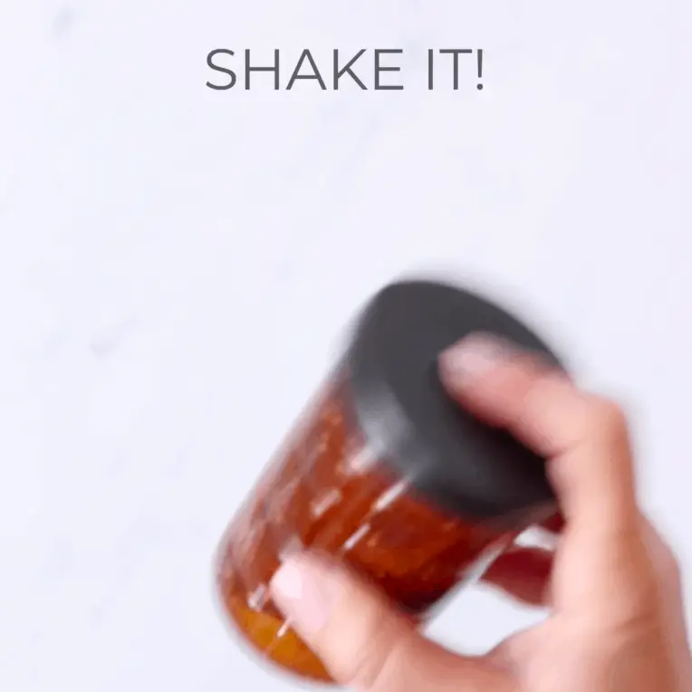 A hand shaking a jar with salad dressing